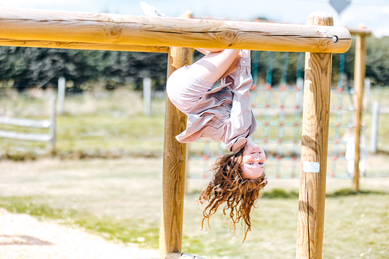 Child hanging upside down on climbing frame